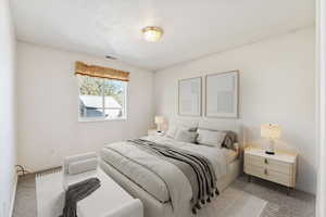 Bedroom featuring light colored carpet and a textured ceiling