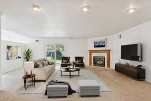Living area with light carpet, a tile fireplace, and a textured ceiling