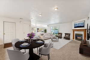 Carpeted dining space with a fireplace and a textured ceiling