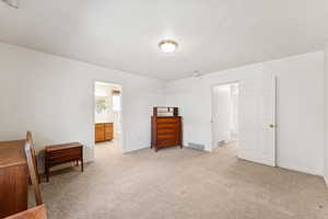 Primary bedroom with light carpet and connected bathroom