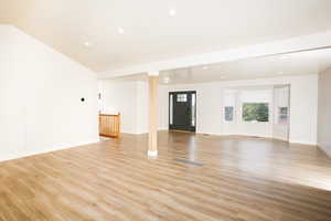 Unfurnished living room featuring light wood-style floors, recessed lighting, and vaulted ceiling