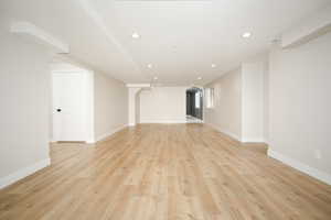 Unfurnished living room featuring recessed lighting, arched walkways, and light wood-style floors