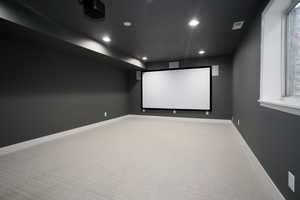Carpeted home theater with recessed lighting and baseboards