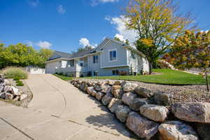 Single story home with brick siding, a front lawn, driveway, board and batten siding, and an attached garage