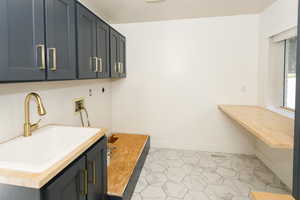 Laundry area with hookup for a washing machine, light tile patterned flooring, and cabinet space