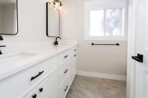 Full bathroom featuring double vanity and baseboards