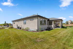 Rear view of property featuring a yard, stucco siding, a patio area, and a sunroom