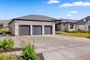 Prairie-style home featuring stone siding, a mountain view, and driveway
