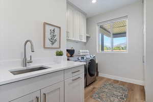 Laundry area featuring light wood-style flooring, cabinet space, separate washer and dryer, and recessed lighting