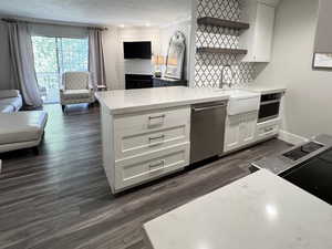Kitchen with open floor plan, white cabinets, a peninsula, dark wood-style floors, and open shelves