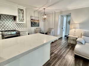 Kitchen featuring backsplash, stainless steel electric range oven, white cabinets, light stone counters, and a textured ceiling