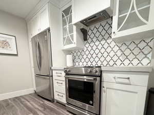 Kitchen featuring white cabinets, decorative backsplash, and appliances with stainless steel finishes