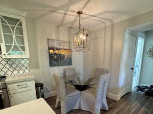 Dining space featuring dark wood finished floors, a textured ceiling, crown molding, and a chandelier