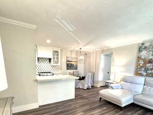 Living room with crown molding, dark wood-style floors, a textured ceiling, and a chandelier