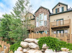 Rear view of property featuring a balcony and stone siding
