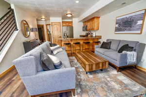 Living room featuring light wood finished floors, a textured ceiling, and stairway