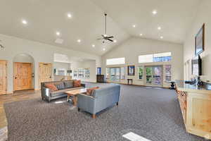 Carpeted living room with high vaulted ceiling, plenty of natural light, recessed lighting, a ceiling fan, and arched walkways
