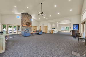 Living area featuring a fireplace, high vaulted ceiling, healthy amount of natural light, dark carpet, and recessed lighting