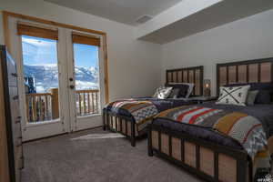Carpeted bedroom with multiple windows, access to outside, and a mountain view