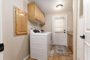 Laundry room with cabinet space, a textured ceiling, washing machine and clothes dryer, and light tile patterned floors