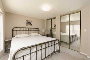 Bedroom featuring light carpet and multiple closets