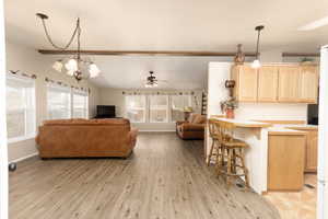 Living area with light wood finished floors, a ceiling fan, and a chandelier