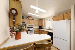 Kitchen with white appliances, vaulted ceiling, a skylight, light countertops, and a peninsula