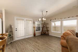 Foyer featuring vaulted ceiling, light wood-type flooring, and a chandelier