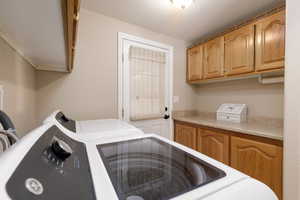 Laundry room featuring washing machine and dryer, a textured ceiling, and cabinet space