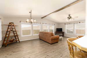 Living area with light wood-style flooring, plenty of natural light, ceiling fan, and a chandelier