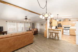 Living room with a chandelier, a ceiling fan, and light wood-style flooring