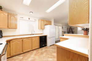 Kitchen with light countertops, light brown cabinets, and white appliances