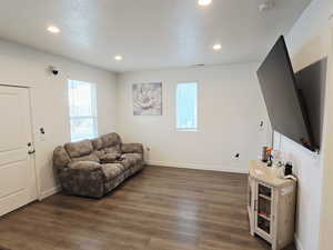 Living room with dark wood-type flooring, recessed lighting, and a textured ceiling