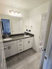 Bathroom with double vanity, a stall shower, light tile patterned floors, and connected bathroom