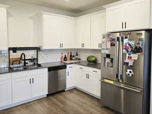Kitchen with appliances with stainless steel finishes, white cabinetry, dark wood-style flooring, and decorative backsplash