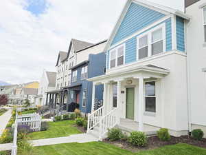 View of side of property with a residential view, a porch, and a lawn