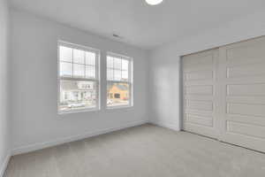 Unfurnished bedroom with light colored carpet and a closet