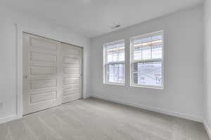 Unfurnished bedroom with light colored carpet and a closet