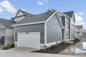 View of home's exterior with roof with shingles, driveway, and a garage