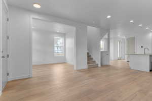 Unfurnished living room with recessed lighting, light wood-style flooring, and stairway