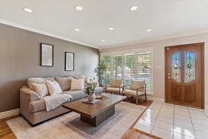 Living room with crown molding, recessed lighting, and light tile patterned flooring