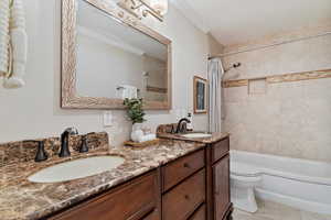 Bathroom featuring shower / bath combo, double vanity, crown molding, and light tile patterned floors
