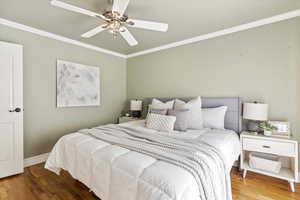 Bedroom with ornamental molding, wood finished floors, and ceiling fan