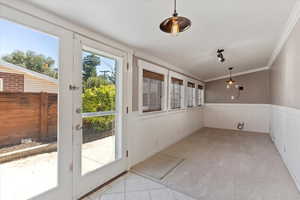 Doorway to outside featuring a wainscoted wall, carpet floors, ornamental molding, and tile patterned floors