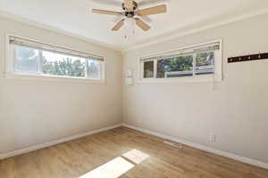 Spare room featuring crown molding, light wood-type flooring, and ceiling fan