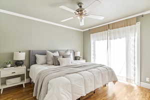 Bedroom featuring wood finished floors, ornamental molding, and a ceiling fan