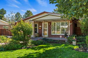 Back of property with brick siding, a yard, and a porch