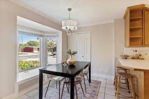 Dining space featuring light tile patterned floors, ornamental molding, and a chandelier