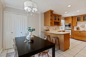 Kitchen with light tile patterned floors, light countertops, tasteful backsplash, pendant lighting, and brown cabinets