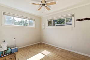 Unfurnished room with light wood finished floors, crown molding, and a ceiling fan